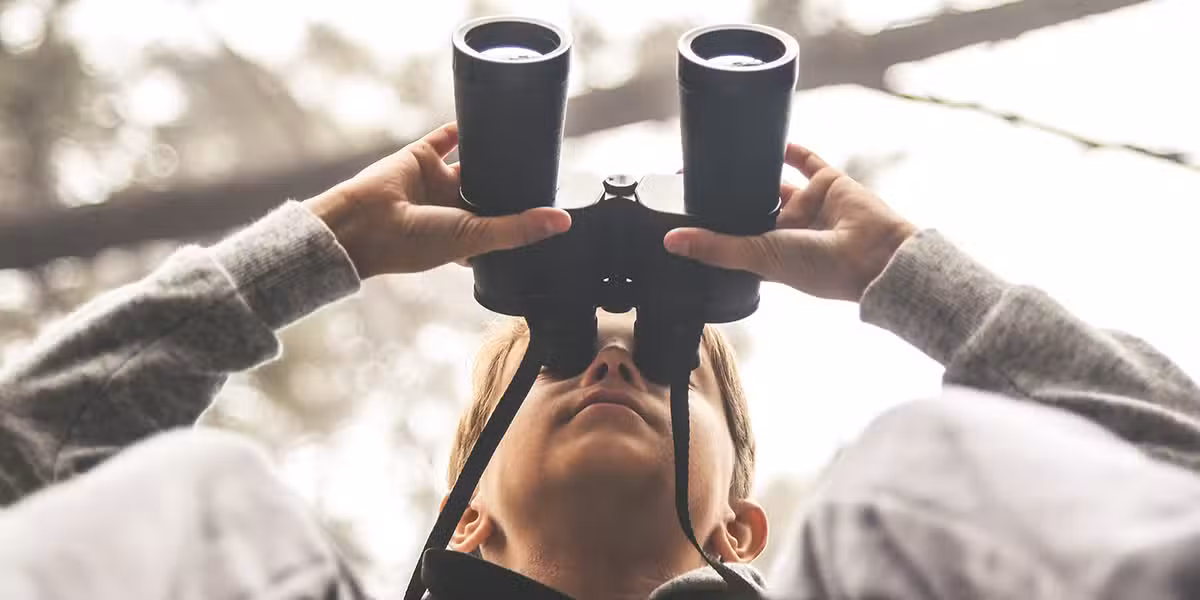 child searching through binoculars looking into the distance