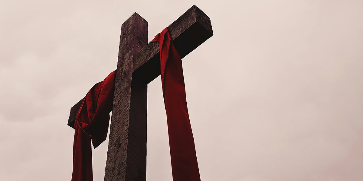 wooden empty cross wrapped in red long cloth