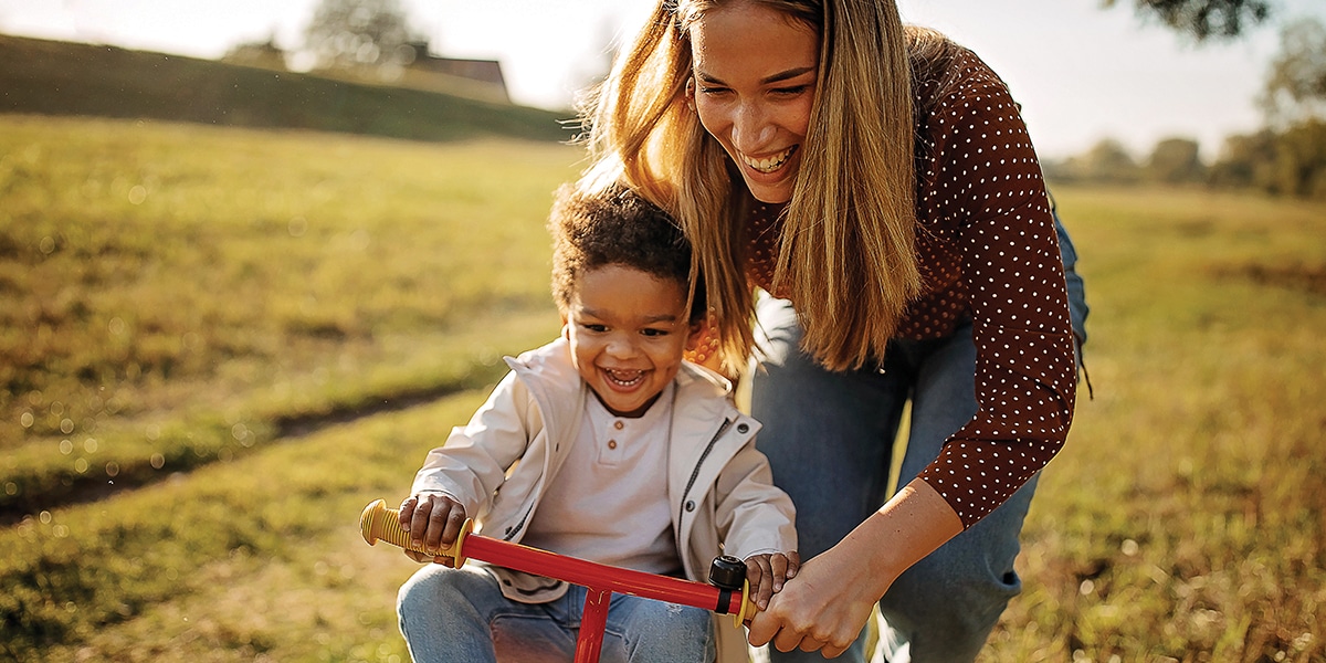 Young mom pushing son on tricycle