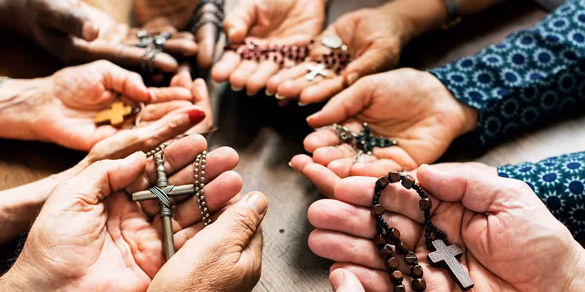 group of people in a circle holding rosaries and praying
