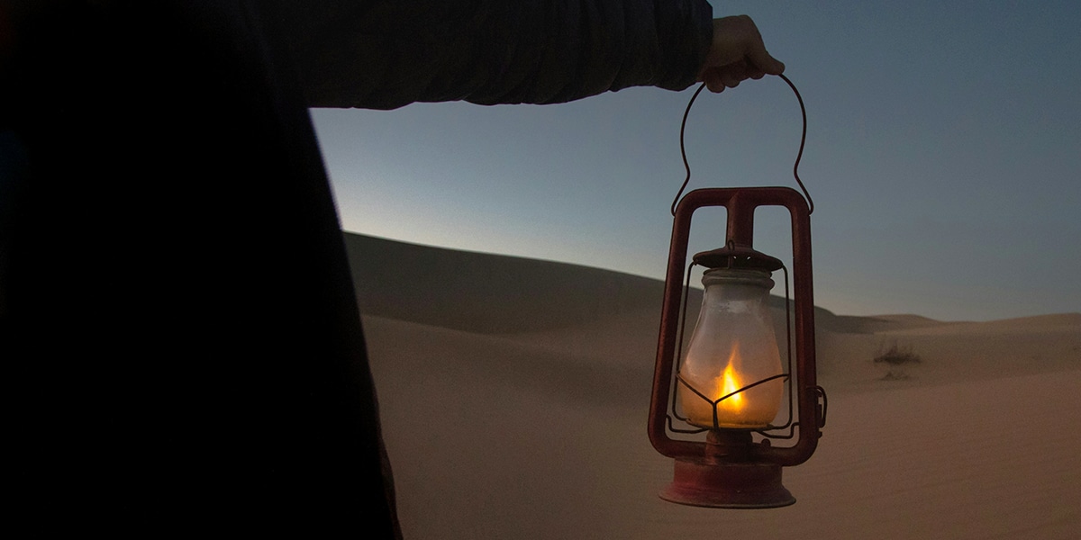 hand holding a lantern in the desert at night
