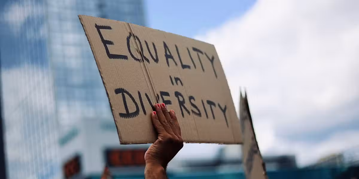 hand holding a sign with the words "Equality in Diversity" written on it.