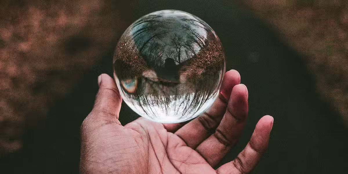 hand holding a glass sphere showing the world.