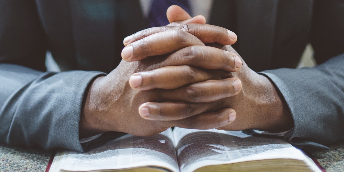 man praying with folded hands.