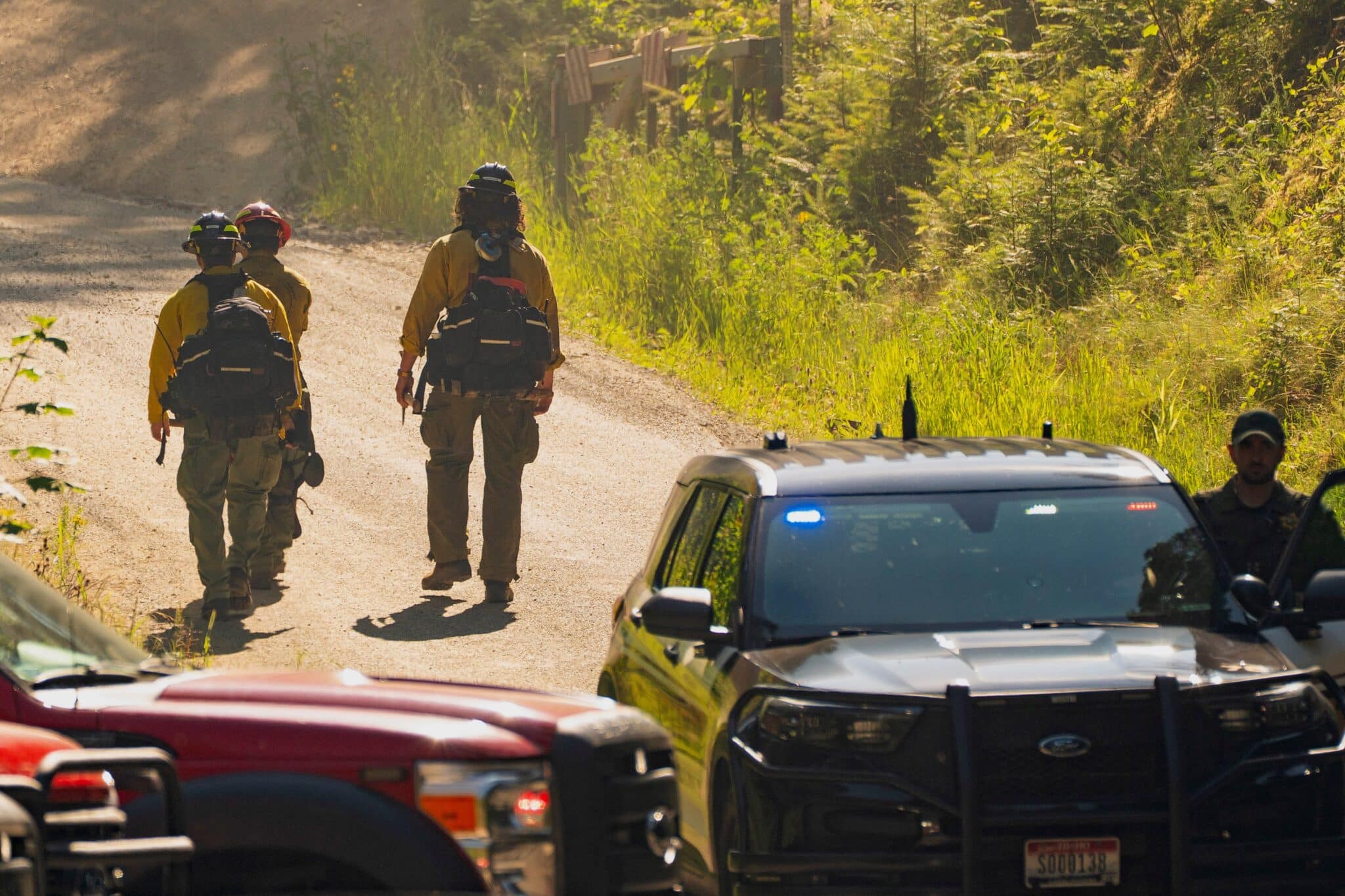 Firefighters walk past a law enforcement checkpoint June 30, 2025, a day after two firefighters were shot dead while responding to a fire and the body of a man was later found with a gun nearby in the Canfield Mountain area outside Coeur d'Alene.