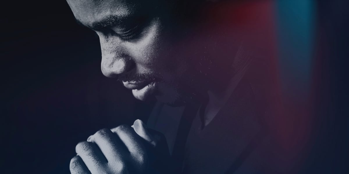 Man praying surrounded by ambient light