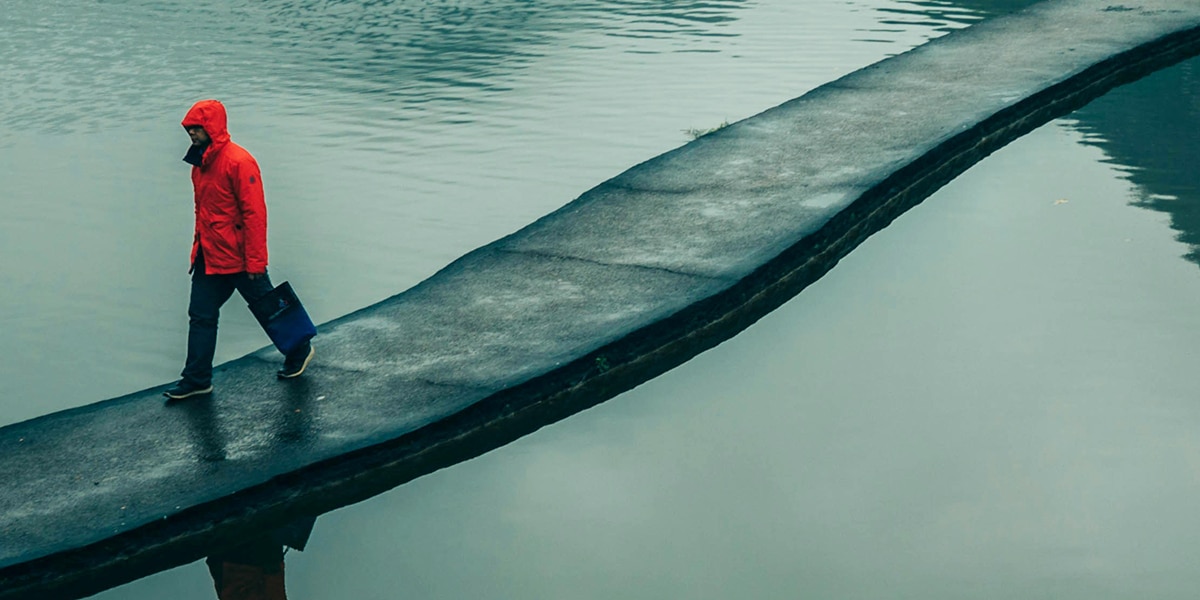 man walking over bridge surrounded by water