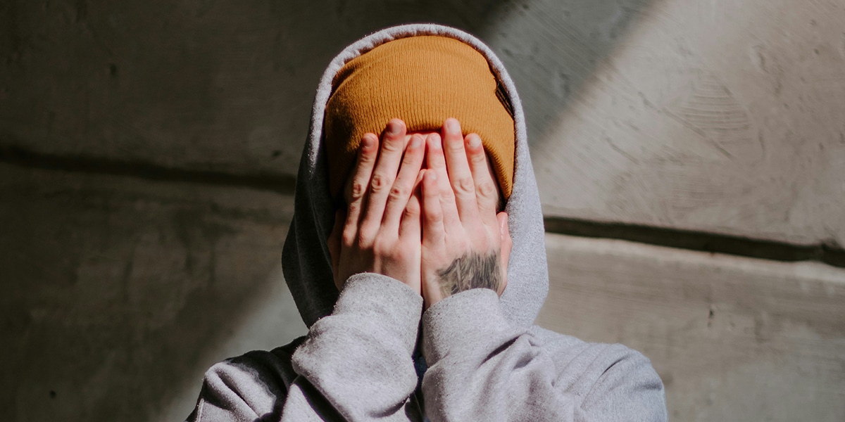 man covering his face with his hands