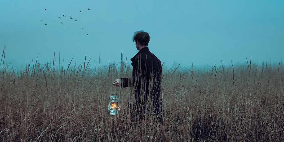 man with a lantern lost in a field.