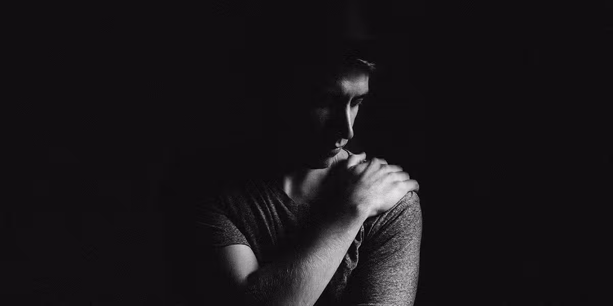 man in pain holding his shoulder with his hand