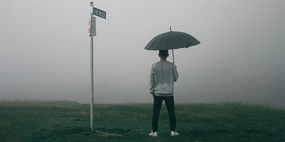 man holding an umbrella standing in front of fog