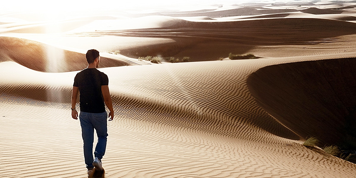 man walking in the desert, looking into the distance.