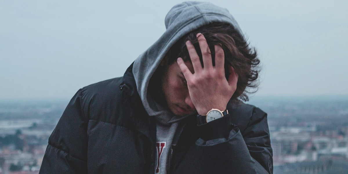 A nervous and worried man holding a hand in front of his face.