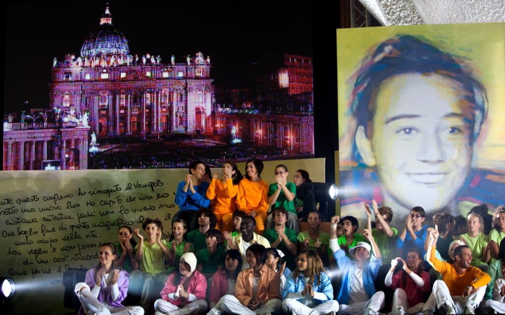 Young people celebrate the beatification of Blessed Chiara Badano, seen in an image at right, during an event in Paul VI hall at the Vatican Sept. 25 after her beatification at the Sanctuary of Divine Love in Rome Sept. 25. Blessed Badano was an Italian teen who witnessed to Christ before dying of cancer in 1990 just before her 19th birthday. (CNS photo/Alessia Giuliani, Catholic Press Photo)