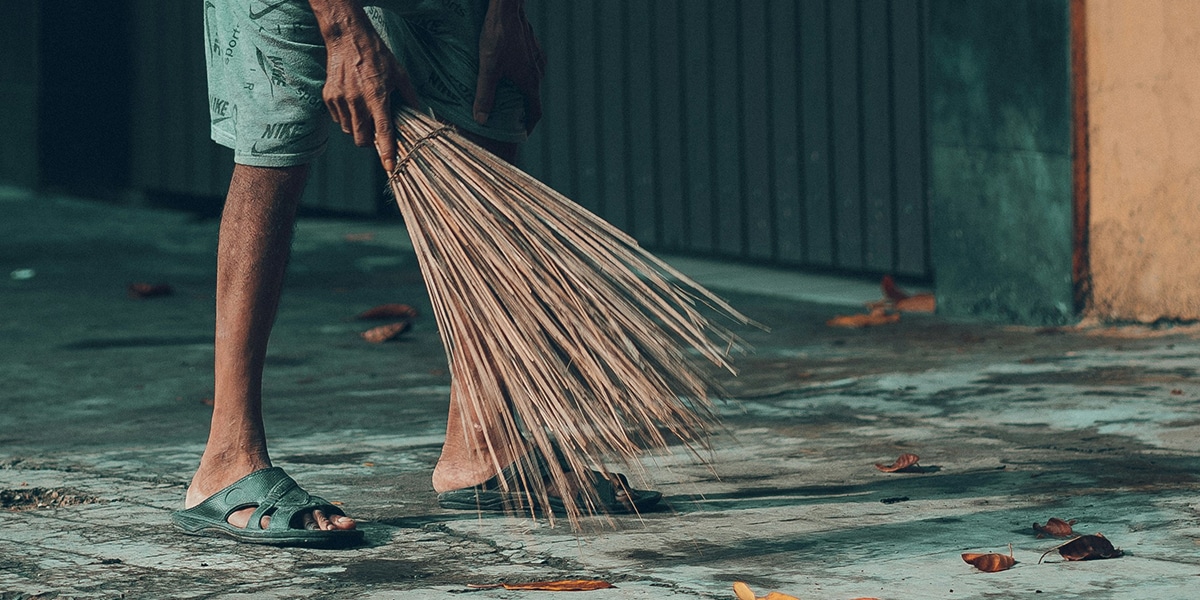 person sweeping the street with a broom