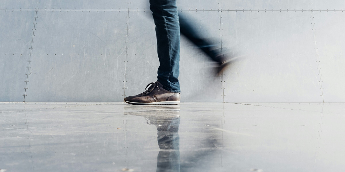 person walking, feet and legs reflecting in the floor