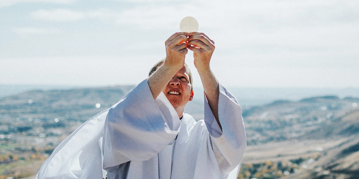 priest holding the sacramental bread to the sky.
