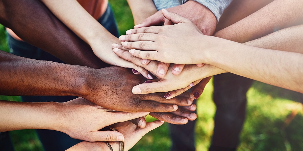 group of people stacking their hands as a sign of solidarity and teamwork