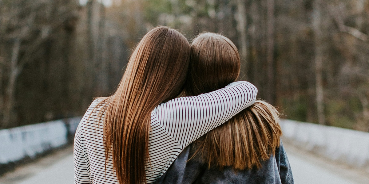Two women friends embracing, one comforting the other.