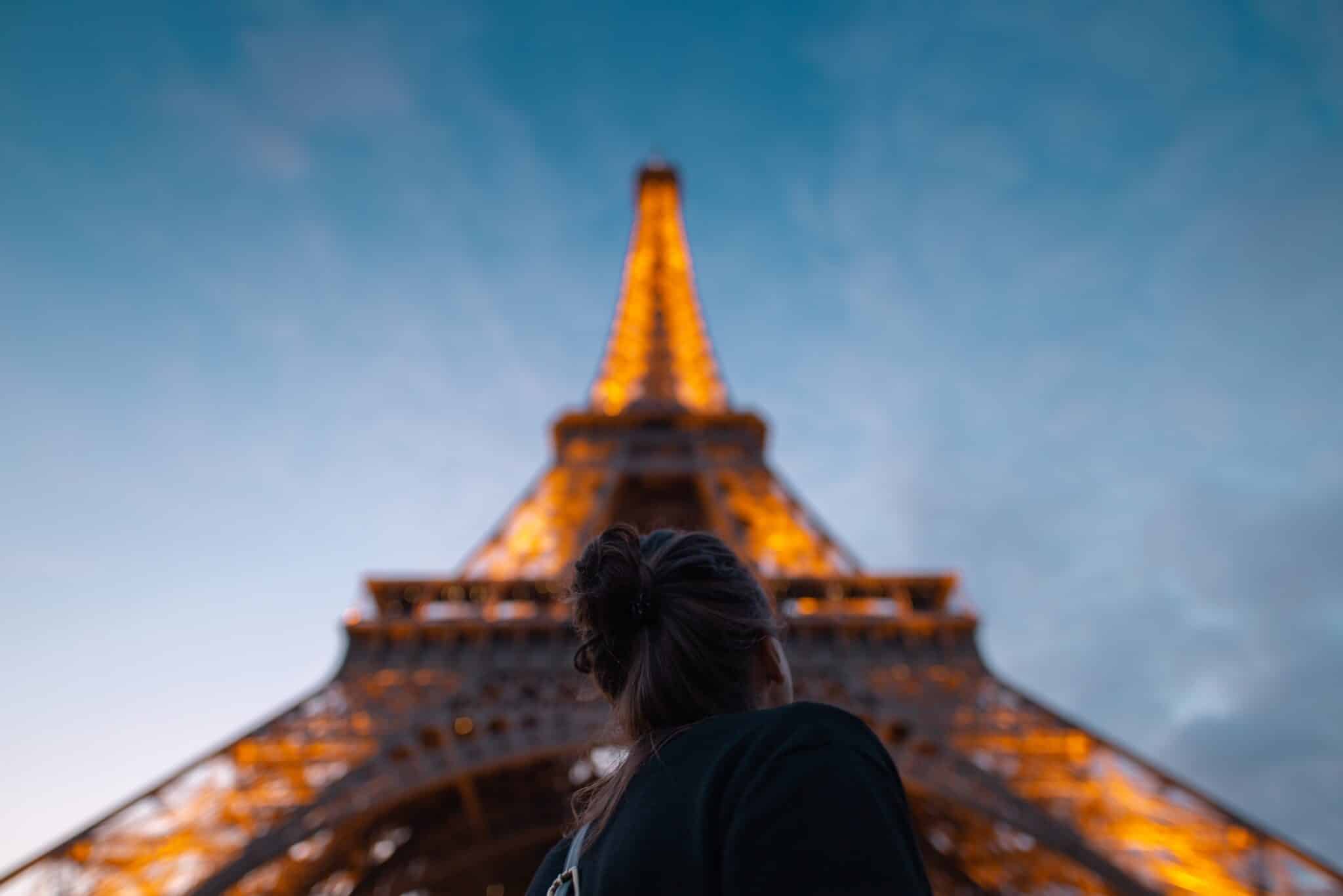 Woman stands under the Eiffel Tower | Photo by Christian Burri on Unsplash