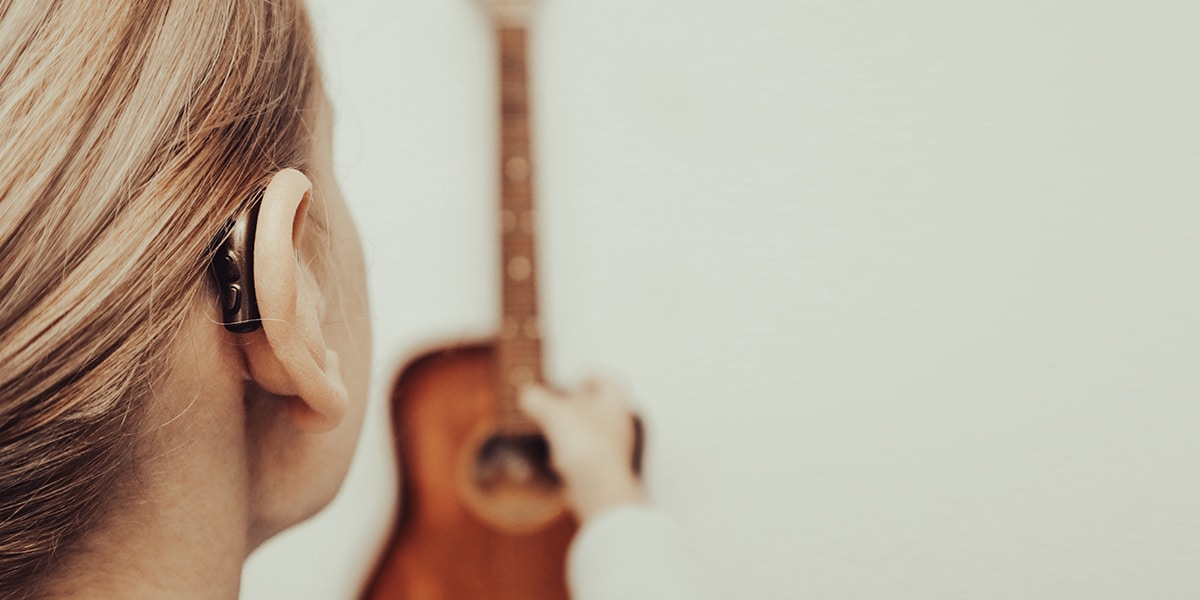 woman with a hearing aid holding a guitar