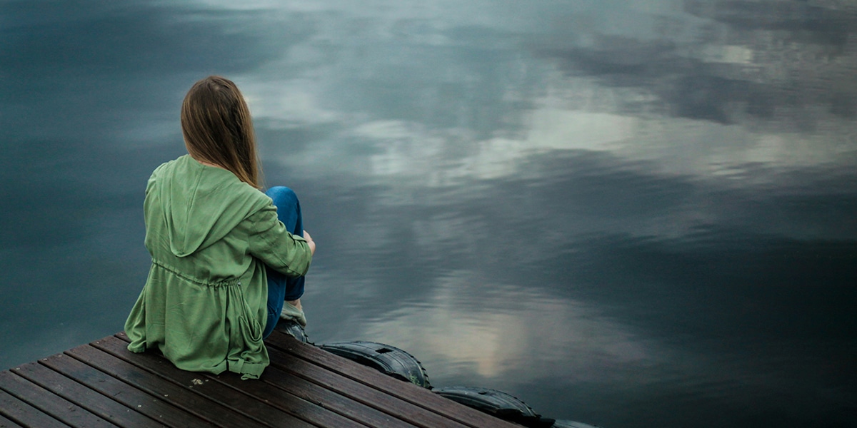 Woman sitting alone on a pier.