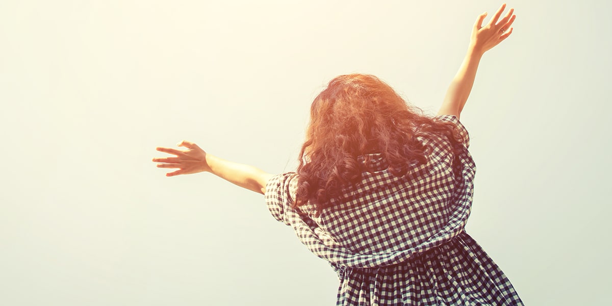 woman raising her arms to the sky in prayer